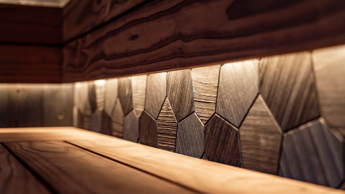 Modern sauna interior with decorative wooden wall panels and warm LED backlighting